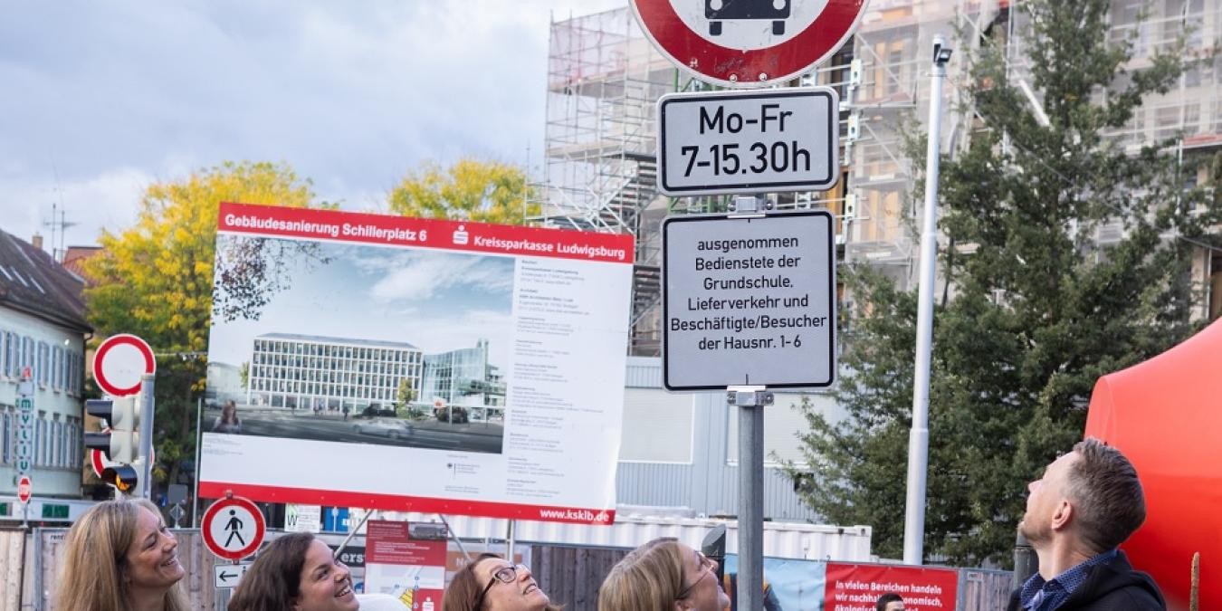 Ein Mann und vier Frauen blicken nach oben auf mehrere Verkehrszeichen.