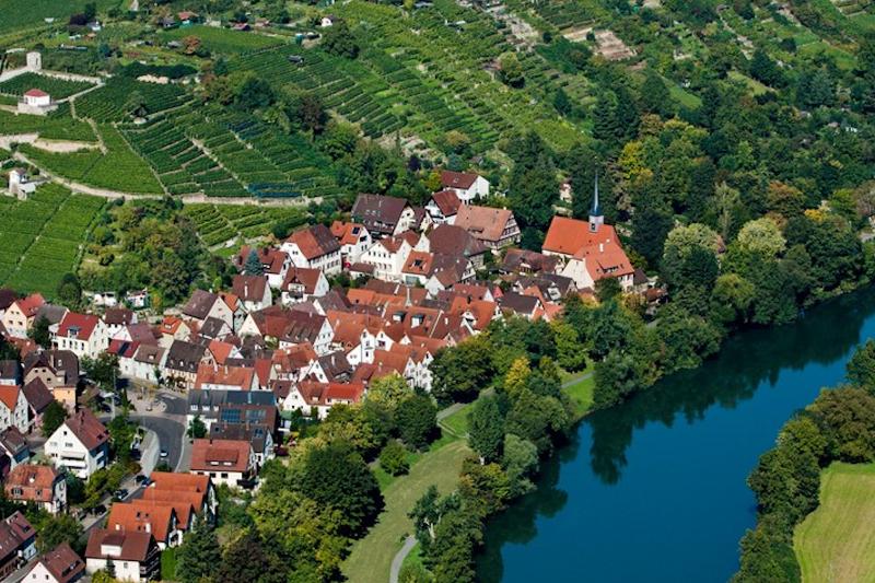 Bild aus der Vogelperspektive auf den Stadtteil Hoheneck. Man sieht den Neckar, Häuser, Felder und Bäume.