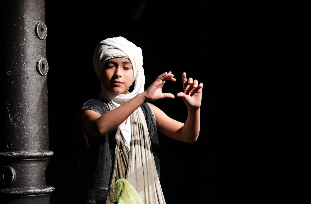 Ein Junge mit Turban steht auf einer Theaterbühne