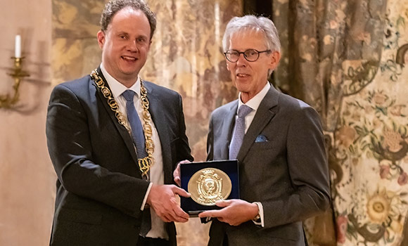 Die beiden Männer halten zusammen die große, goldene Bürgermedaille.