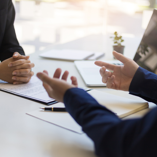zwei Personen in einer Beratungssituation sitzen an einem Tisch