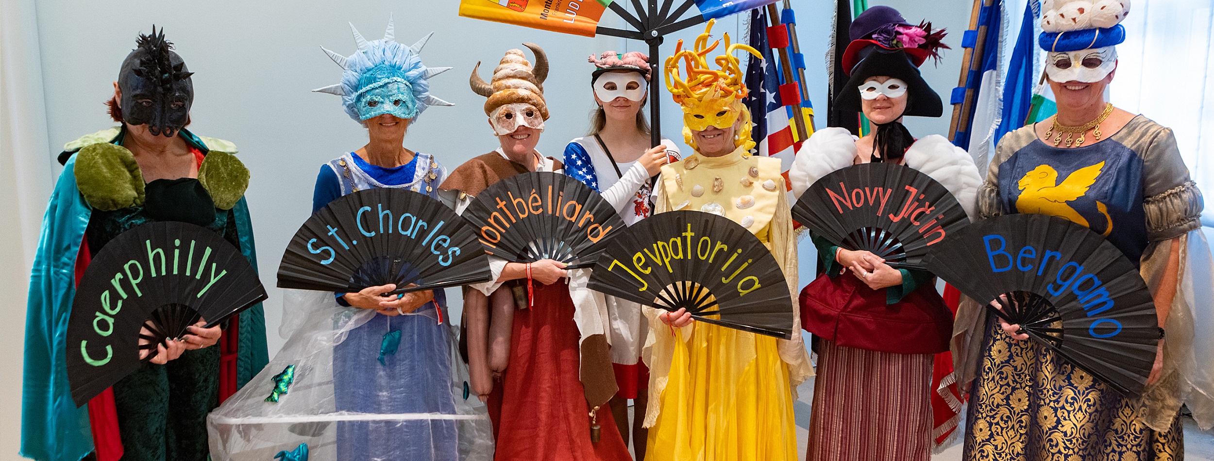 Kostümträger mit den Fächern auf denen die Namen der Partnerstädte stehen