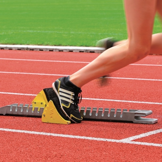 Sportvereine und Sportangebote Beine, die sich aus einem Startblock herausdrücken
