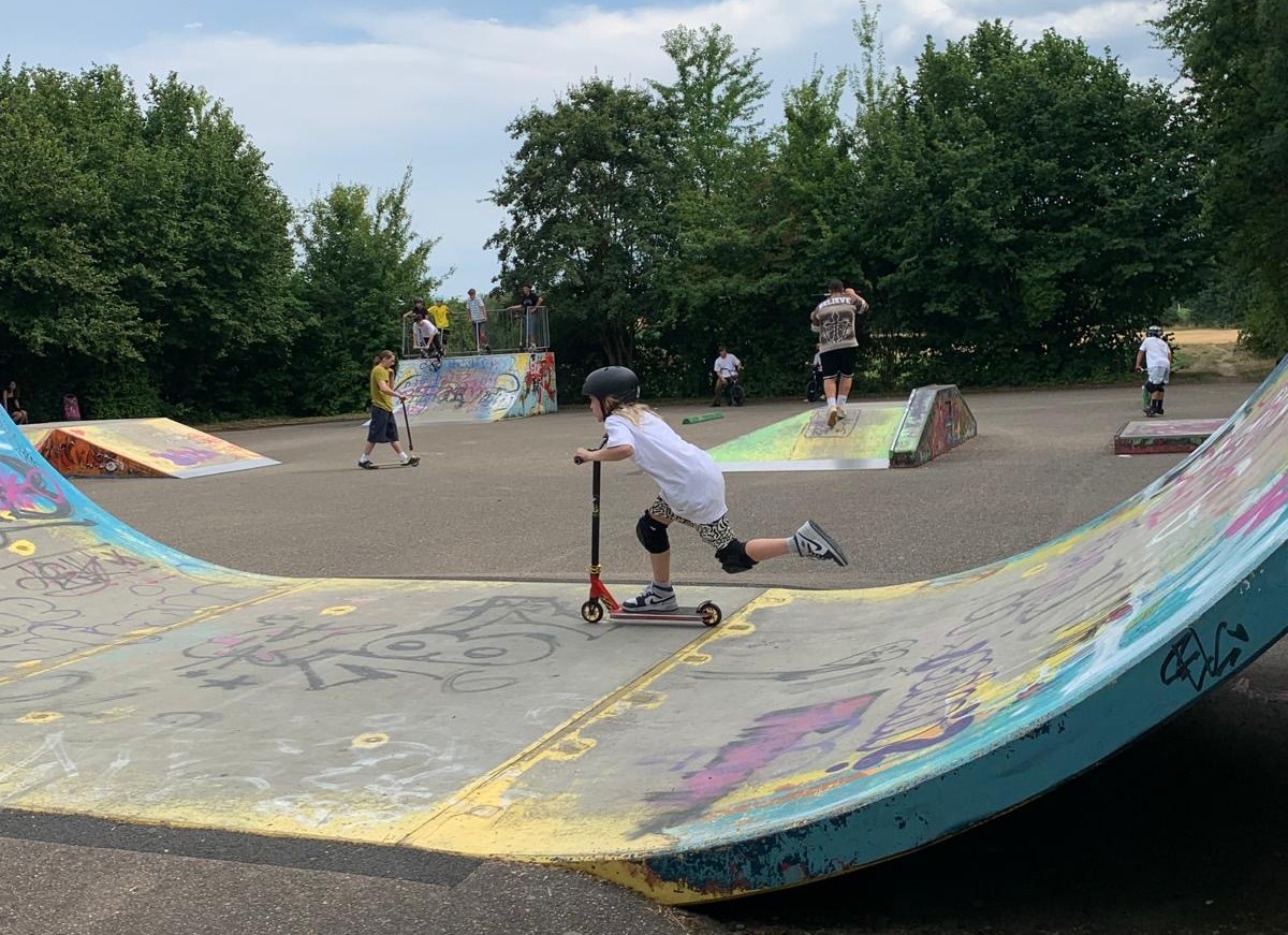 Kind fährt mit Roller auf bunt bemalter Rampe