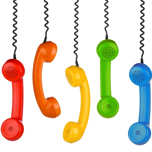 5 verschiedenfarbige Telefonhörer hängen an ihren Kabeln nach unten