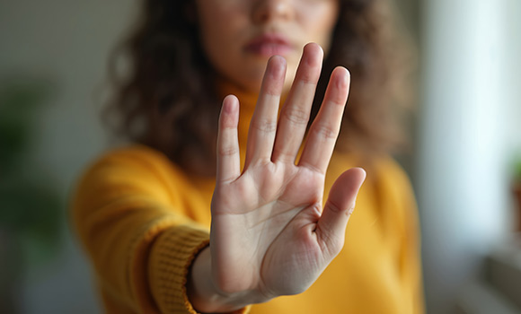 Eine Frau hält ihre Hand Richtung Kamera, um "Stopp" zu signalisieren.