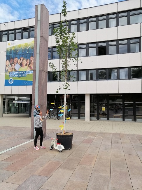 Frau mit Kind schaut die Kärtchen am Baum der Inspiration an