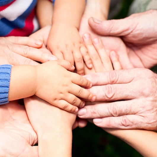 Hände von Menschen unterschiedlichen Alters übereinander gelegt nach dem Motto "alle für einen"