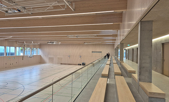 Das Innere der Halle mit Bänken der Zuschauertribüne und Spielfeld.