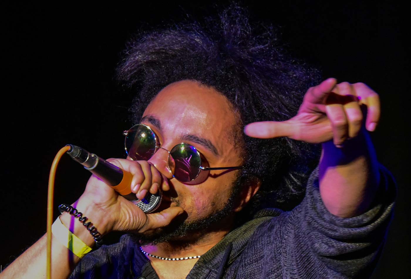 Ein Rapper mit Sonnebrille performt einen Song mit Mikro in der Hand.