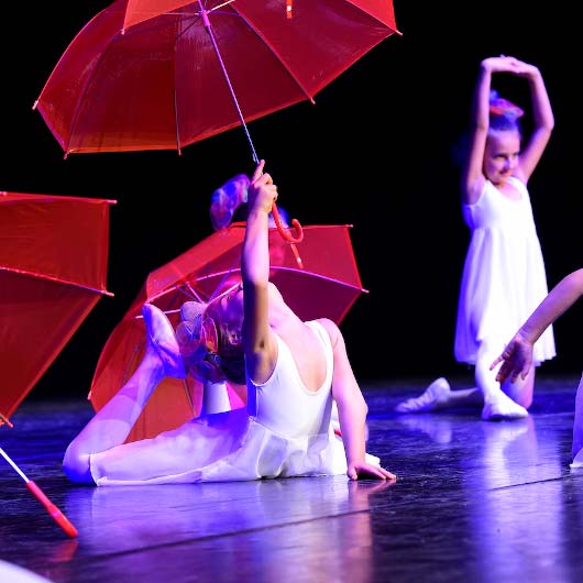 Tanzende Mädchen mit roten Regenschirmen