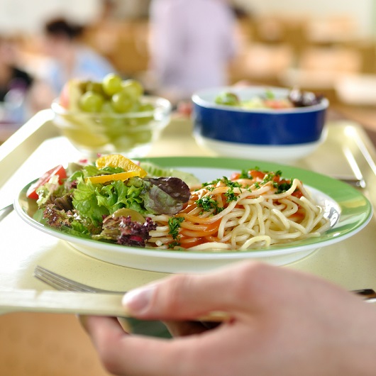 Nahaufnahme eines Tabletts mit Spaghetti, Salat und einer Orangenscheibe.