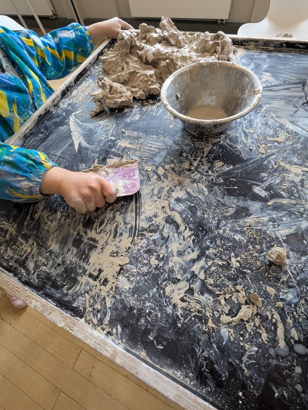 Kinder an Tisch mit Wasserschale fürs Töpfern