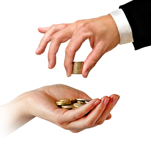 Die Hand eines Mannes gibt Kleingeld in eine weibliche Hand