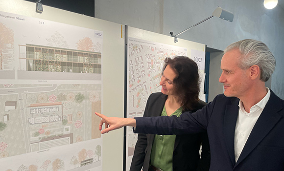 Andrea Schwarz und Matthias Weißer schauen auf ein Plakat.