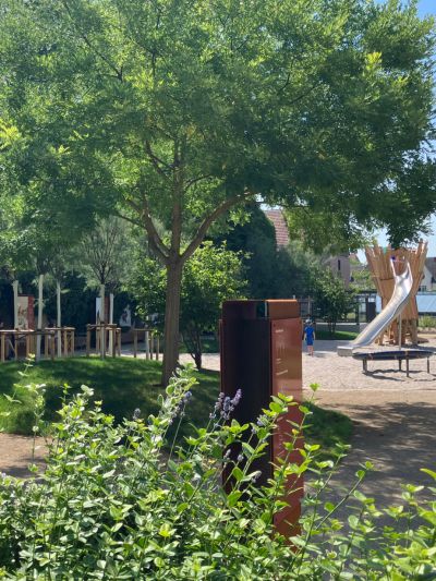 Spielplatz, Wiese, Bäume und Aufsteller