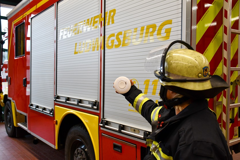 Feuerwehrangehörige in Schutzkleidung vor Einsatzfahrzeug