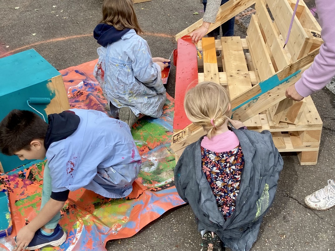 Drei Kinder malen Holzpaletten