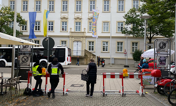 In der Oberen Marktstraße - gegenüber dem Rathaus - stehen zwei mobile Absperrungen. Hinter einer der Absperrungen stehen zwei Security-Kräfte. Eine Frau geht zwischen den beiden Absperrungen hindurch.