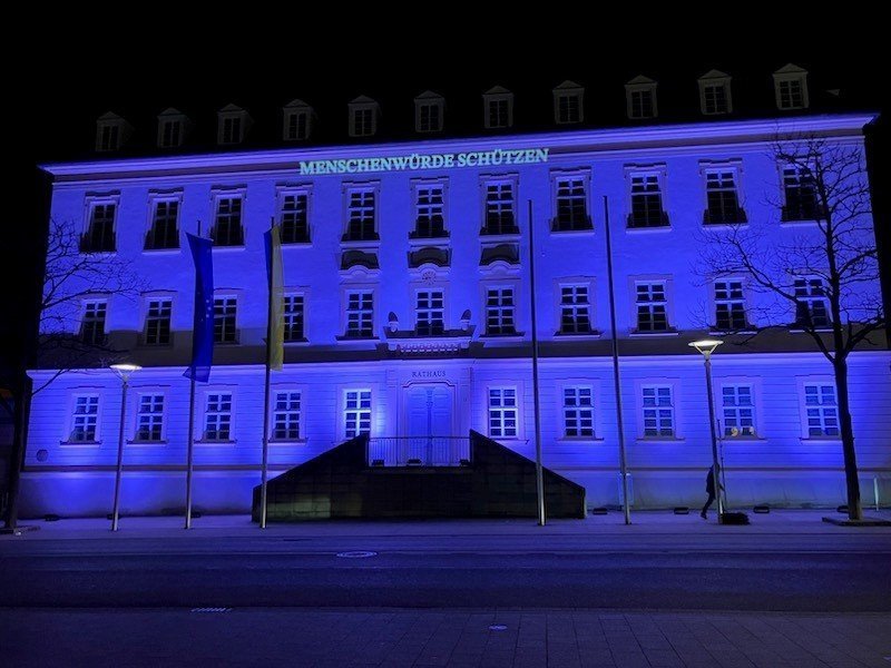 Menschenwürde schützen! Beleuchtung in der Kampagnenfarbe der Internationalen Wochen gegen Rassismus: flieder