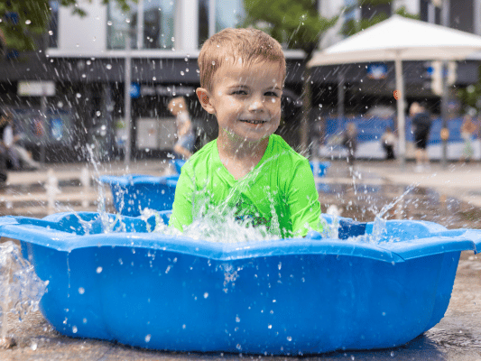 Kind sitzt in Wasserbecken