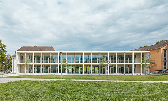 Schulgebäude mit verglastem Neubau, der zwei Altbauten verbindet.