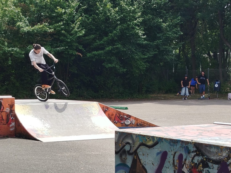 Person mit Fahrrad fährt von bunt bemalter Rampe runter