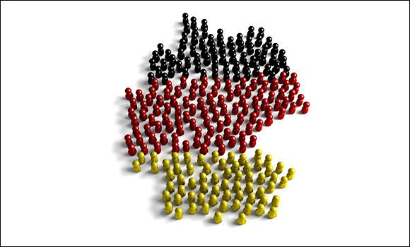 Viele Spielfiguren in Schwarz, Rot und Gold bilden den Grundriss Deutschlands nach.