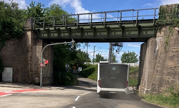 Bus fährt unter der Eisenbahnbrücke August-Bebel-Straße hindurch.