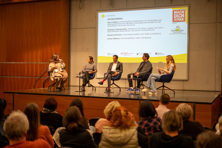 Publikum im Vordergrund, Podiumsdiskussion im Hintergrund