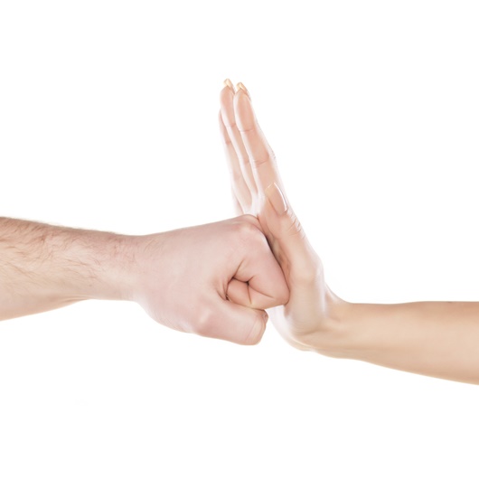 eine weibliche Hand wehr die Faust einer männlichen Hand ab