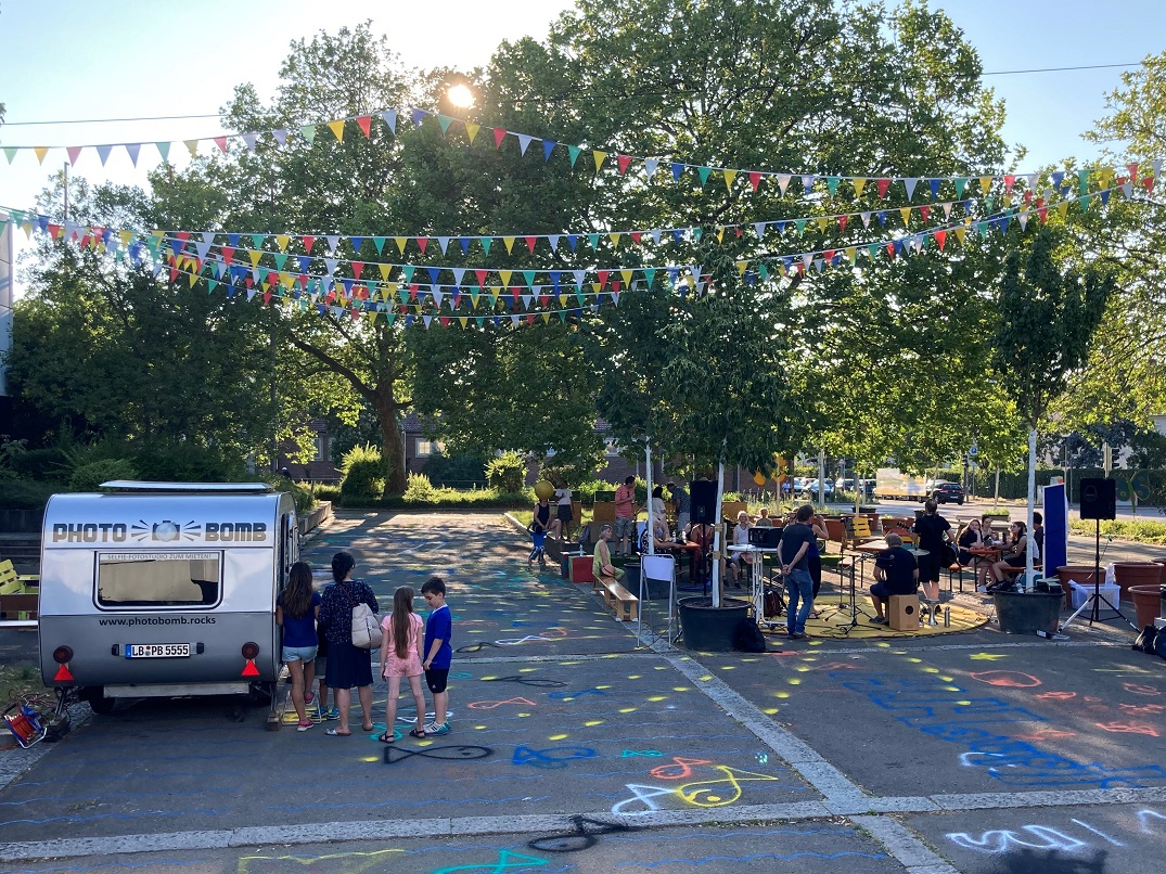 Hocketse Personen beim Foodtruck und sitzend an Biertischen