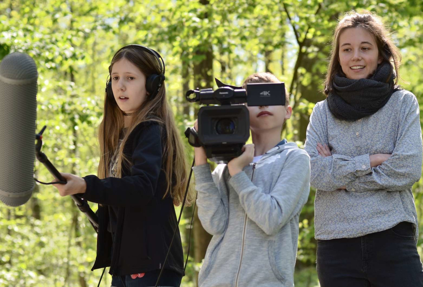 Zwei Mädchen und eine junge Erwachsener mit Kamera und Stabmikrofon