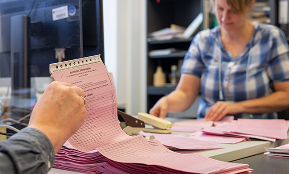 Wahlhelfer halten Stimmzettel in den Händen.