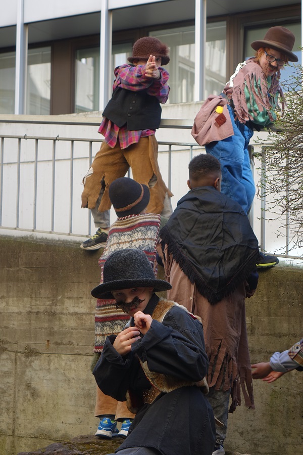 Kinder in Kostümen machen Räuberleitern an einem Haus