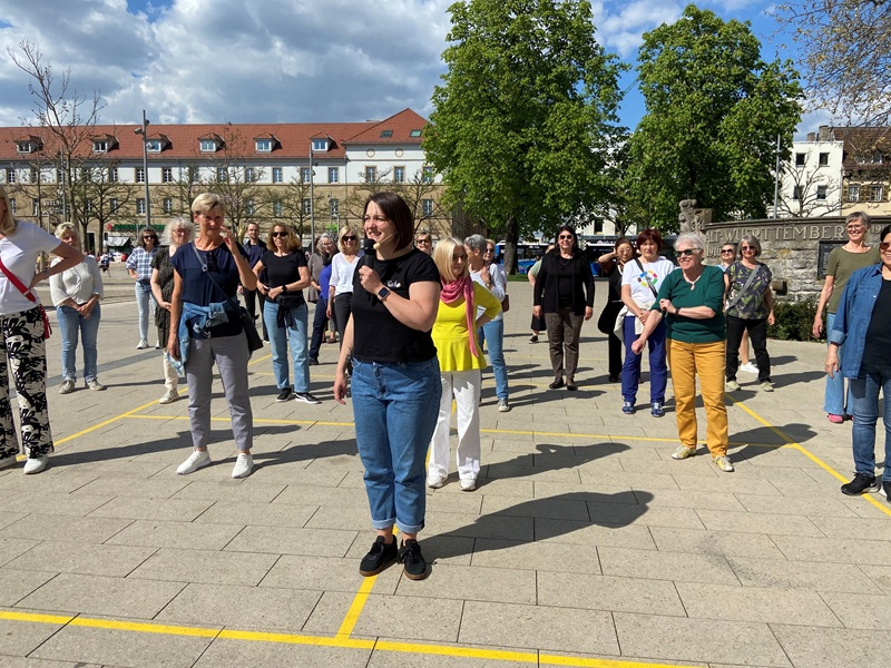 Kursleiterin mit Mikrofon vor Teilnehmenden auf Arsenalplatz