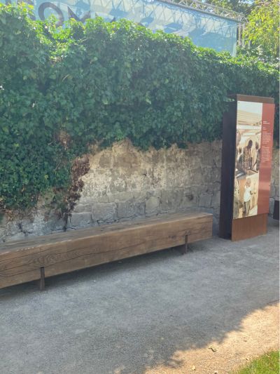 Sitzgegelenheit und Aufsteller vor begrünter Mauer