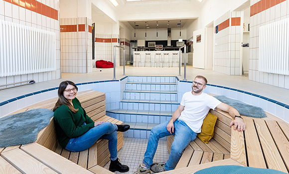 Irina Aust und Johannes Albrecht sitzen in der Sitzecke im ehemaligen Tauchbecken.