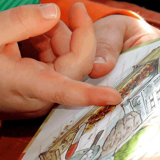 Kinderhand die auf ein Bilderbuch zeigt