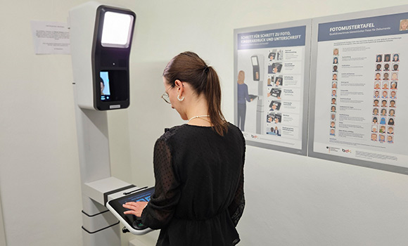 Eine Frau nimmt Passbilder am Point-ID-Terminal auf.