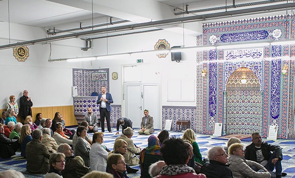 Mehrere Menschen sitzen auf dem Boden in einer Moschee.