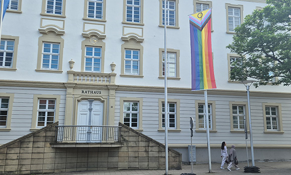 Fahnenmast mit Regenbogenflagge vor dem Rathausgebäude 