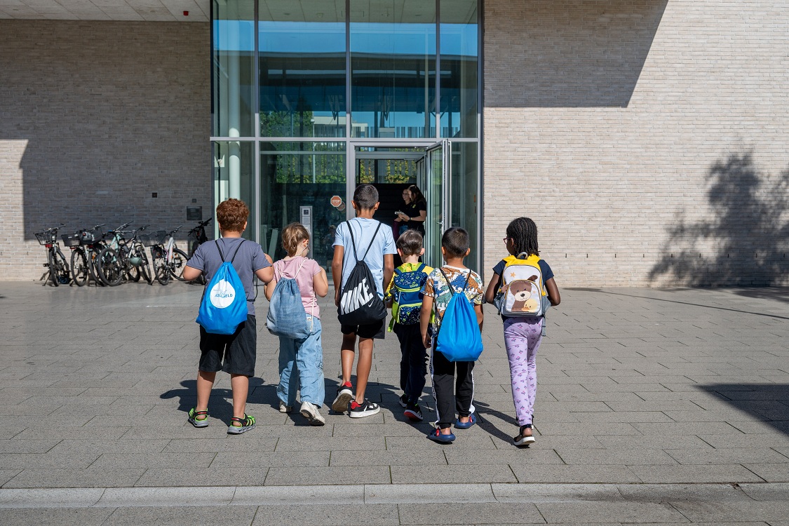 Schulkinder von hinten laufen zum Eingang des Schwimmbads