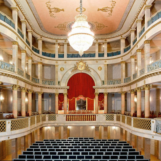 Innenraum des historischen Schlosstheaters mit Kronleuchter an der Decke.