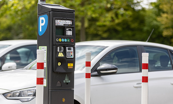 Parkscheinautomat und parkende Autos.