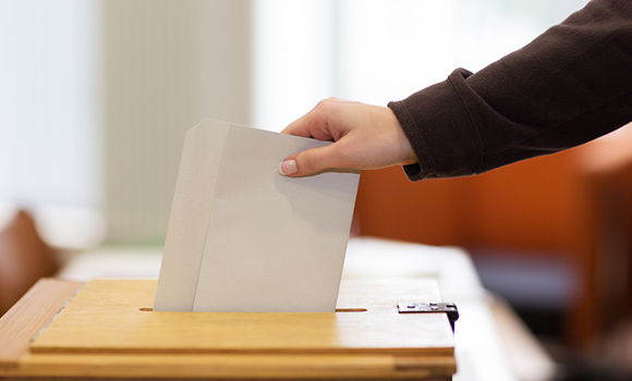 Ein Zettel wird in eine Wahlurne gesteckt.