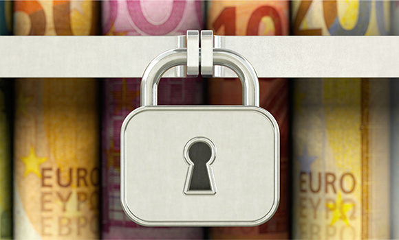 Das Symbolbild zeigt ein Vorhängeschloss. Dahinter befinden sich Euro-Geldscheine.