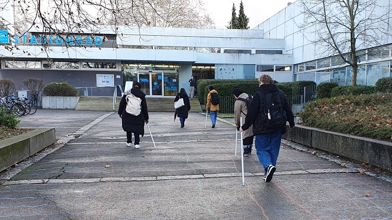 Personen mit Rucksack ziehen Stäben mit Kreide auf dem Asphalt