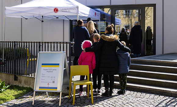 Menschen warten vor einem Gebäude.