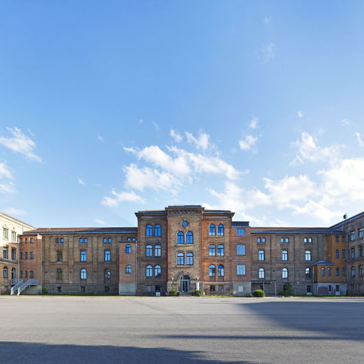 Frontalansicht der Karlskaserne vom Hof aus. Die Karlskaserne ist ein großer Backsteinbau.